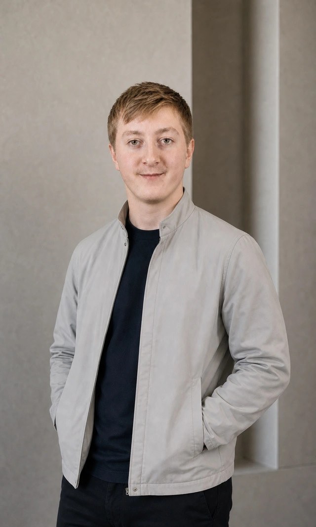 Porträt von Moritz Zinecker, Gründer und Geschäftsführer von Audecius: junger Mann mit kurzen blonden Haaren, hellgrauer Jacke und dunklem Shirt vor einer grauen Wand.